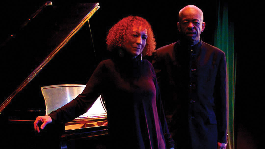 Iqua Colson and Adegoke Steve Colson standing beside a grand piano on stage